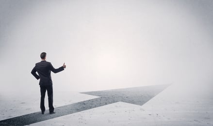 A professional businessman thinking while standing on a black arrow pointing forward in grey space concept